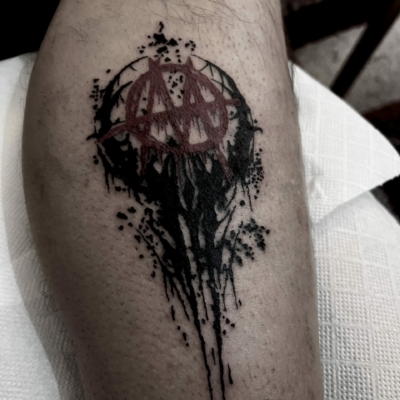 Dark symbol tattoo for a male client on his leg, mixed red and black ink.