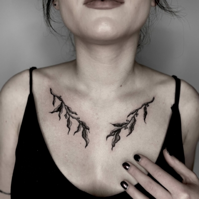 Clevage tattoo of olive branches for a female client, decorative and delicate design in a dark mood.