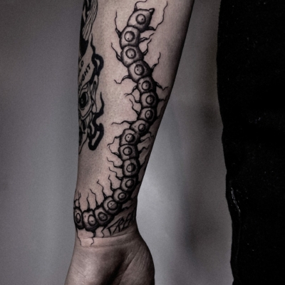 Centipede tattoo on a male arm in a dark creepy style.