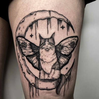 Cat on the moon tattoo on a thigh.