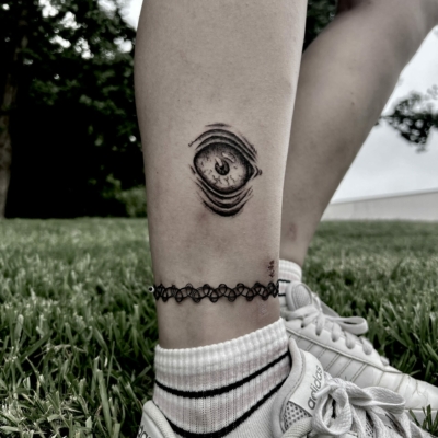 Eye leg tattoo in a creepy dark horror style.